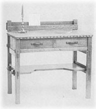 Writing-table in gray oak; top in sage green leather; wrought iron pulls